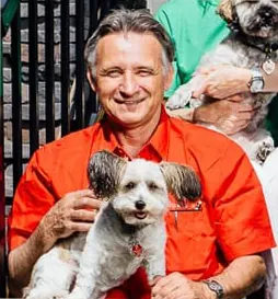 Michael Thibert, President and Founder of Michael Homes, holding a small white dog