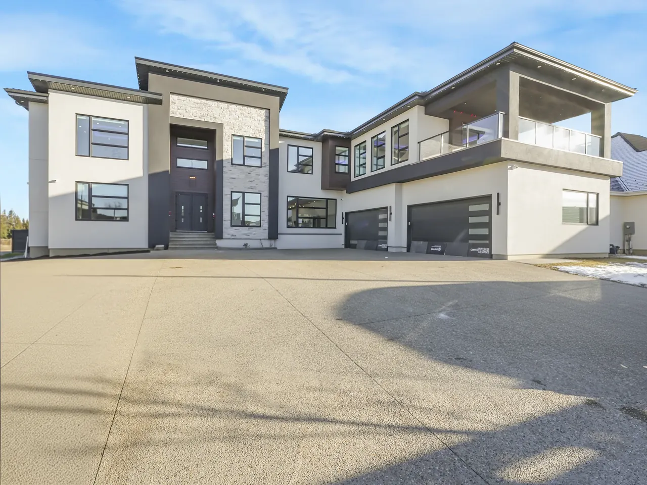 Front of a modern custom home in Sherwood Park with stone, stucco and dark window frames